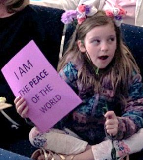 young girl holding a sign that says 'I am the Peace of the World'